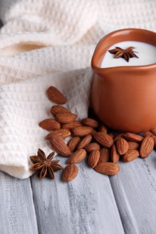 Almond milk in jug with almonds in bowl,